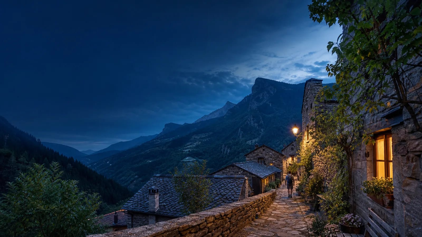 Pueblo de montaña al anochecer, con viviendas de piedra y un valle arbolado
